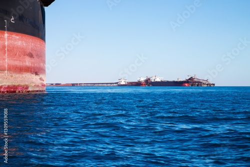 ore ship's hull with outloading and ships in distance photo