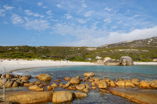 secluded white sand beach with rocks in foreground photo