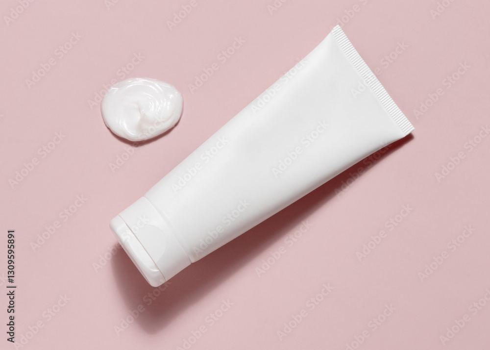 White blank squeeze cosmetic tube near cream smear on light pink top view, mockup White blank squeeze cosmetic tube near cream smear on light pink top view, mockup