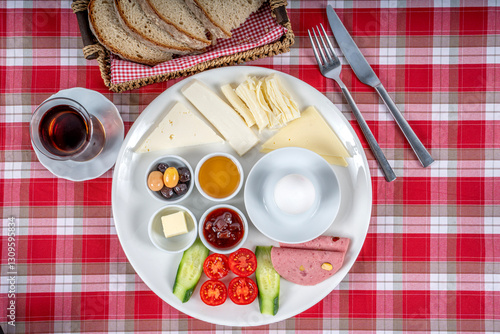 Traditional Turkish breakfast plate. The plate contains cheese varieties, jam, honey, eggs, tomatoes, cucumber, butter, olives and salami.