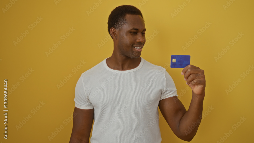 Young man smiling at a credit card against a bright yellow background, showcasing modern financial independence and confidence. Young man smiling at a credit card against a bright yellow background, showcasing modern financial independence and confidence.