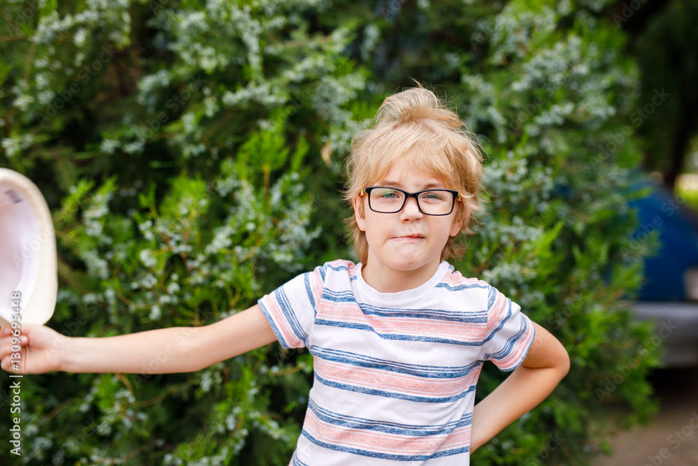A young blonde boy with large glasses and a straw sunhat is featured in a portrait A young blonde boy with large glasses and a straw sunhat is featured in a portrait