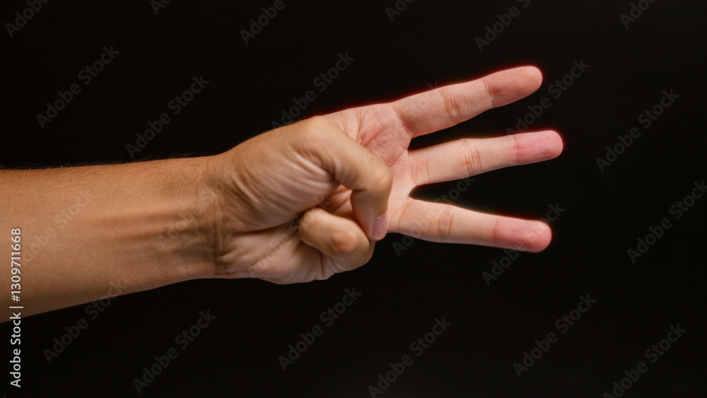 Man showing three fingers against a black background with a closeup focus on the hand in color. Man showing three fingers against a black background with a closeup focus on the hand in color.