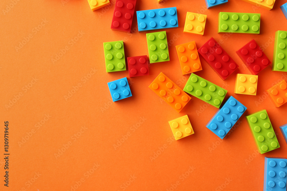 Obraz premium Construction toy. Colorful building bricks on orange background, flat lay with space for text