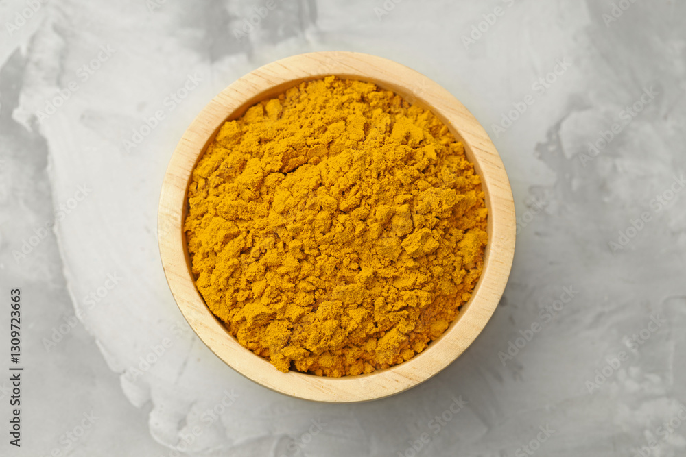 Fototapeta premium Turmeric powder in bowl on light grey table, top view