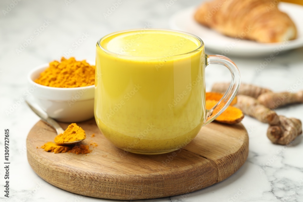 Delicious turmeric latte, powder and rhizomes on white marble table, closeup Delicious turmeric latte, powder and rhizomes on white marble table, closeup