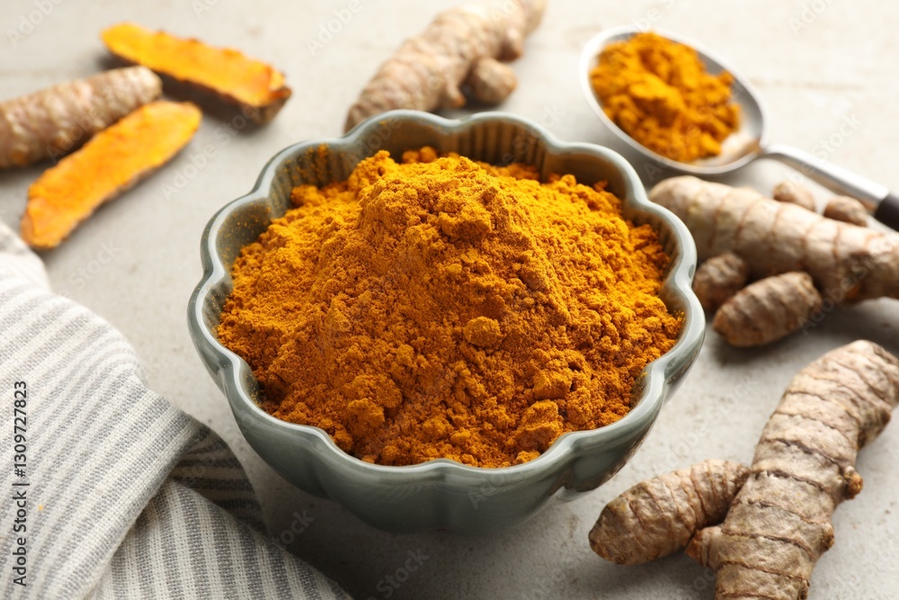 Aromatic turmeric powder in bowl and fresh roots on light grey table, closeup Aromatic turmeric powder in bowl and fresh roots on light grey table, closeup