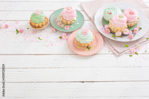 pink and green cupcakes with spring flowers on white wooden background