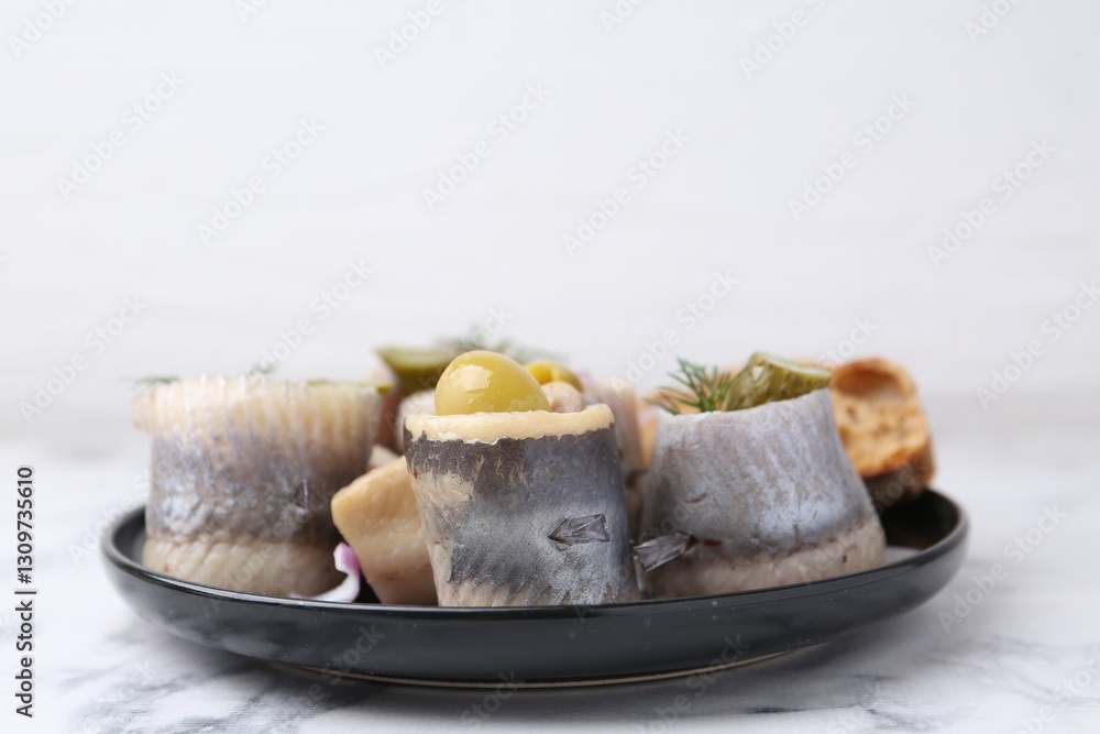 Delicious herring rolls with olives, pickles and dill on light marble table, closeup Delicious herring rolls with olives, pickles and dill on light marble table, closeup