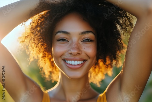 Joyful Young Woman Smiling While Holding Her Hair Against a Vibrant Yellow Ba...