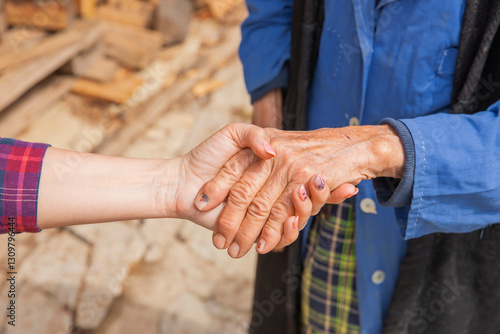 Hand einer alten Frau in der Hand einer jungen Frau