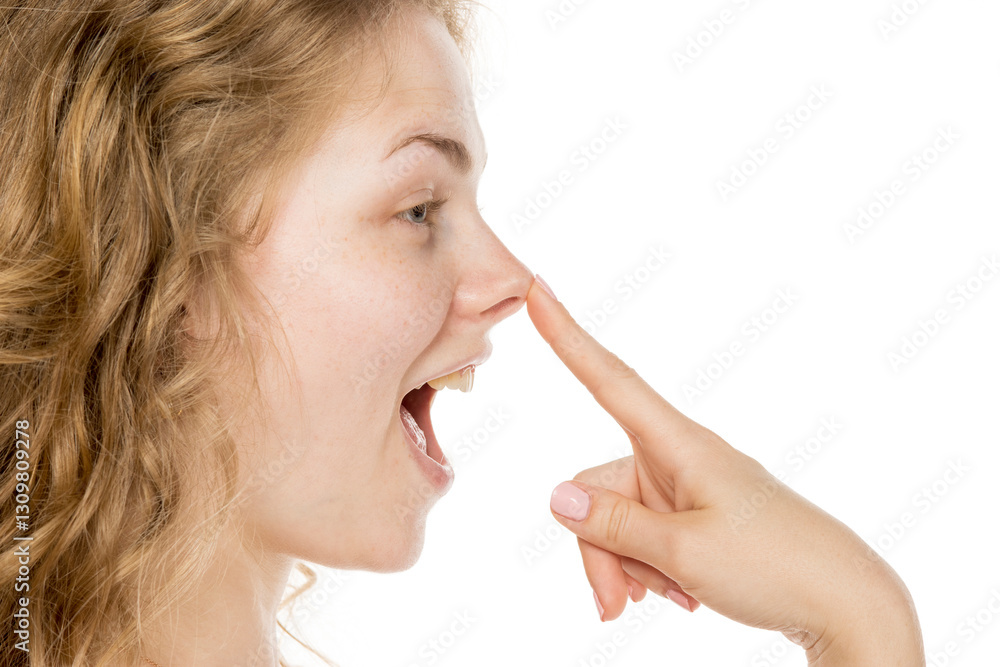 Happy woman touching nose, suggesting rhinoplasty. Profile, curly blonde hair, no makeup, white background Happy woman touching nose, suggesting rhinoplasty. Profile, curly blonde hair, no makeup, white background