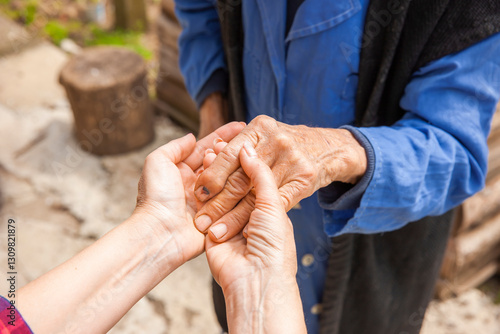 Hand einer alten Frau in der Hand einer jungen Frau
