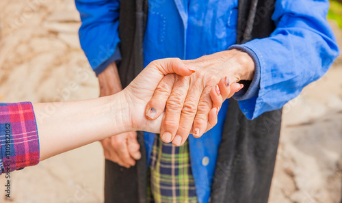 Hand einer alten Frau in der Hand einer jungen Frau