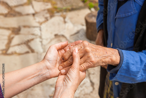 Hand einer alten Frau in der Hand einer jungen Frau