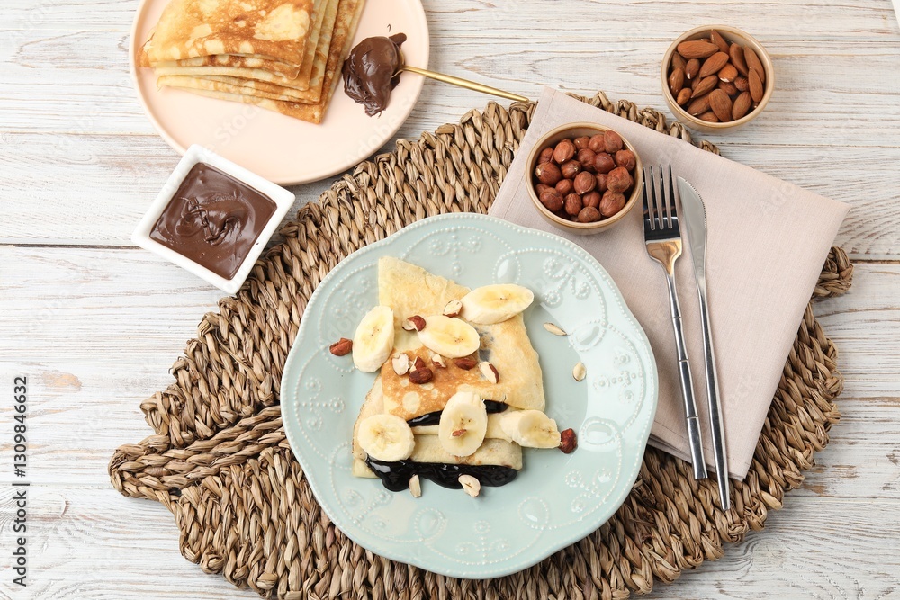 Delicious crepes with banana, chocolate sauce and nuts on wooden table, flat lay Delicious crepes with banana, chocolate sauce and nuts on wooden table, flat lay