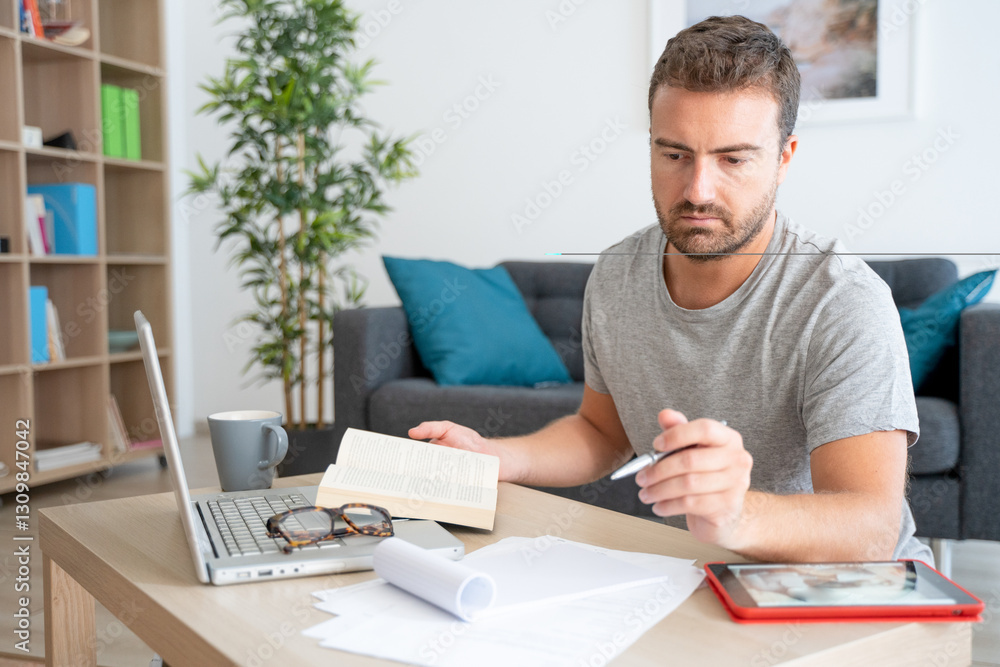 One guy studying at home sitting in front of his computer One guy studying at home sitting in front of his computer