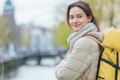 Young caucasian female traveler smiling with yellow backpack outdoors in city.