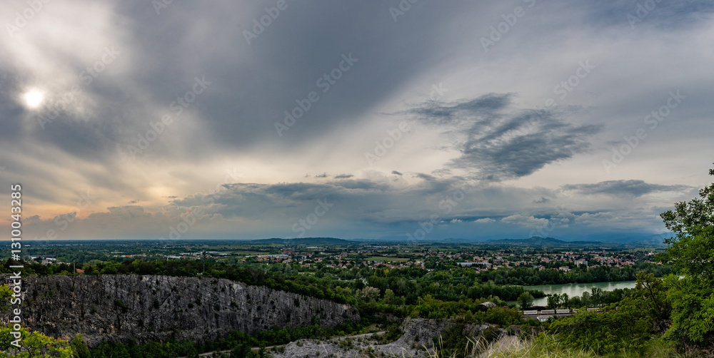 ampia composizione panoramica con vista sul territorio in pianura nell'area nord-est della regione Friuli Venezia Giulia, al tramonto, all'arrivo di un temporale estivo