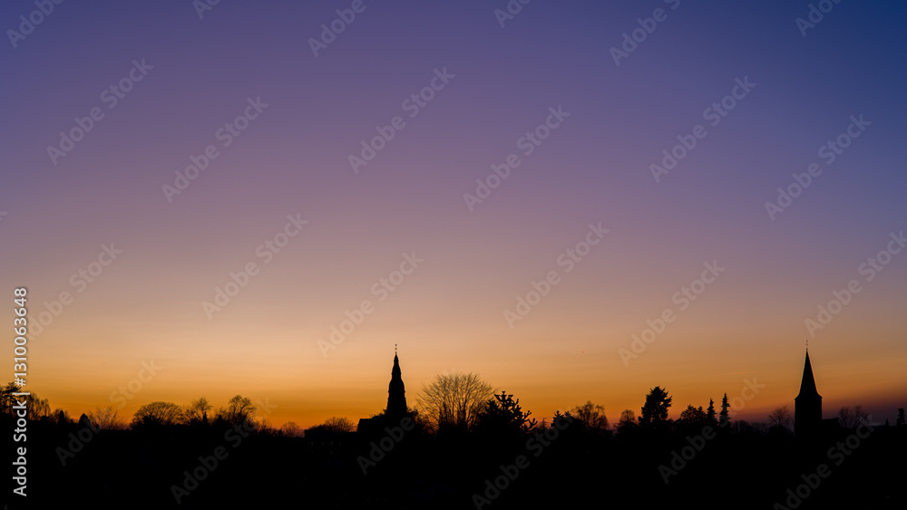 Fototapeta premium sunset at the blue hour with the skyline of the two churches of ratingen homberg with colored sky 