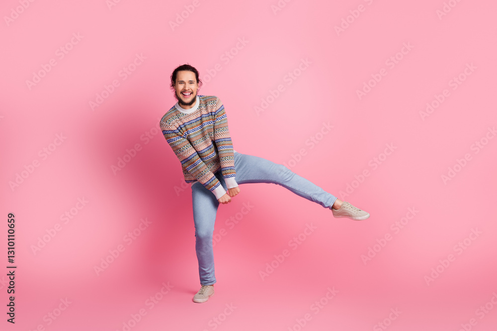 Cheerful man in a stylish sweater showing playful energy against pink background, wearing casual blue jeans and beige sneakers Cheerful man in a stylish sweater showing playful energy against pink background, wearing casual blue jeans and beige sneakers