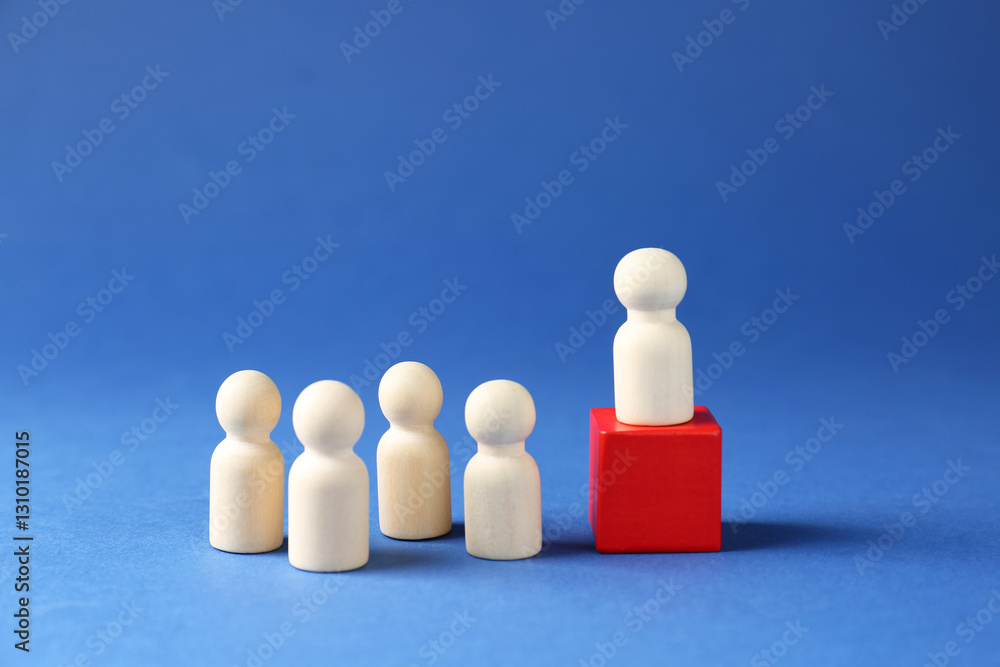Competition concept. Human figure on wooden cube and other ones behind against blue background Competition concept. Human figure on wooden cube and other ones behind against blue background