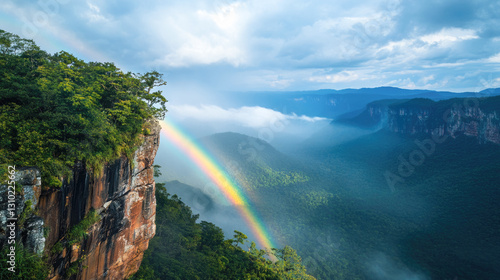 Stunning rainbow over lush mountain landscape with rocky cliff and clouds