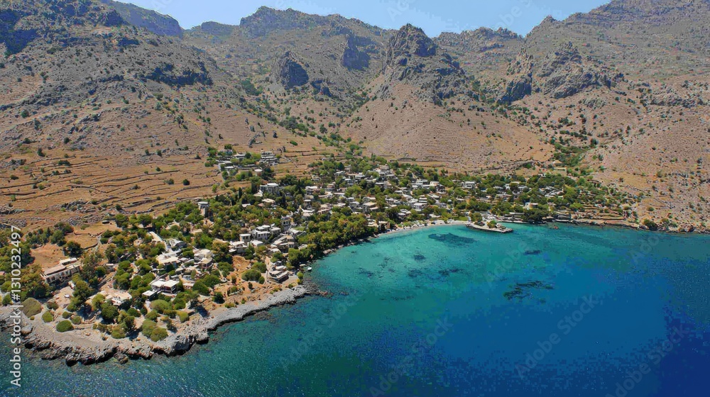 Fototapeta premium Aerial view of Greek village nestled on coastline with turquoise water and mountains