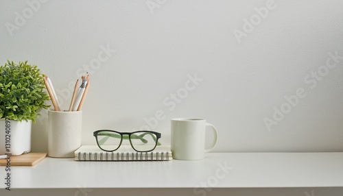 desk with stationery, eyeglasses, notebook, mug and a plant, copy space