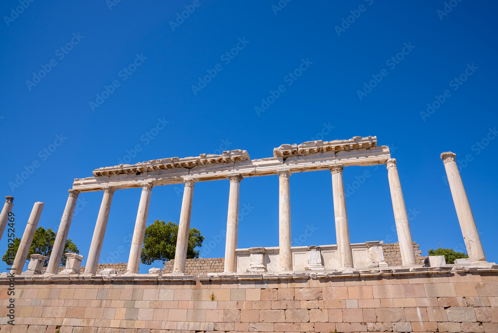 Historical view of greek antique city of Bergama. Ancient architectural landscape with marble columns and walls with a blue background. Ancient city of Pergamon. Archaeology and tourism concept backgr Historical view of greek antique city of Bergama. Ancient architectural landscape with marble columns and walls with a blue background. Ancient city of Pergamon. Archaeology and tourism concept backgr