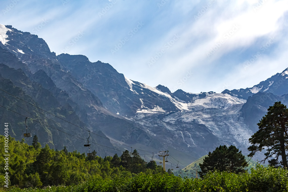 Fototapeta premium Cable car ascending snowy mountain peaks in summer