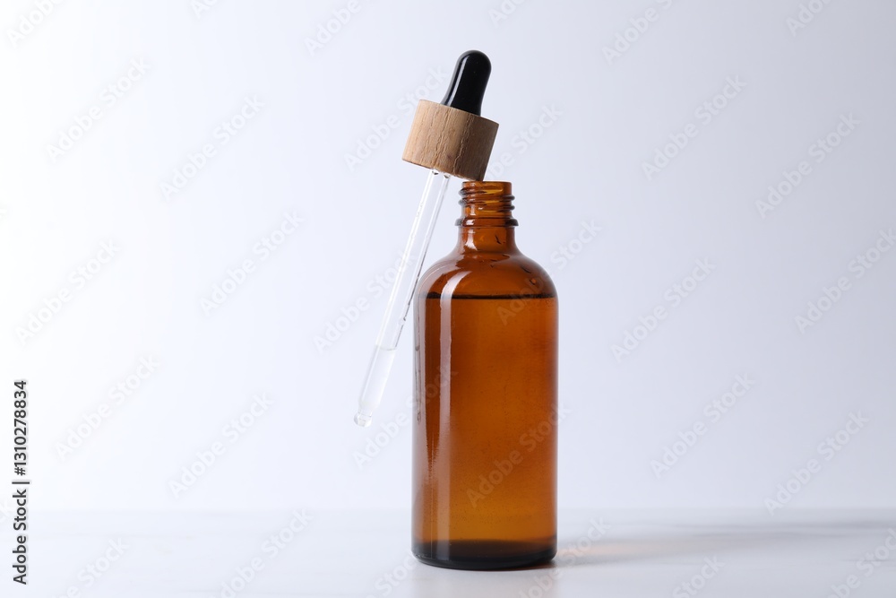 Bottle and pipette of serum on light table, closeup Bottle and pipette of serum on light table, closeup