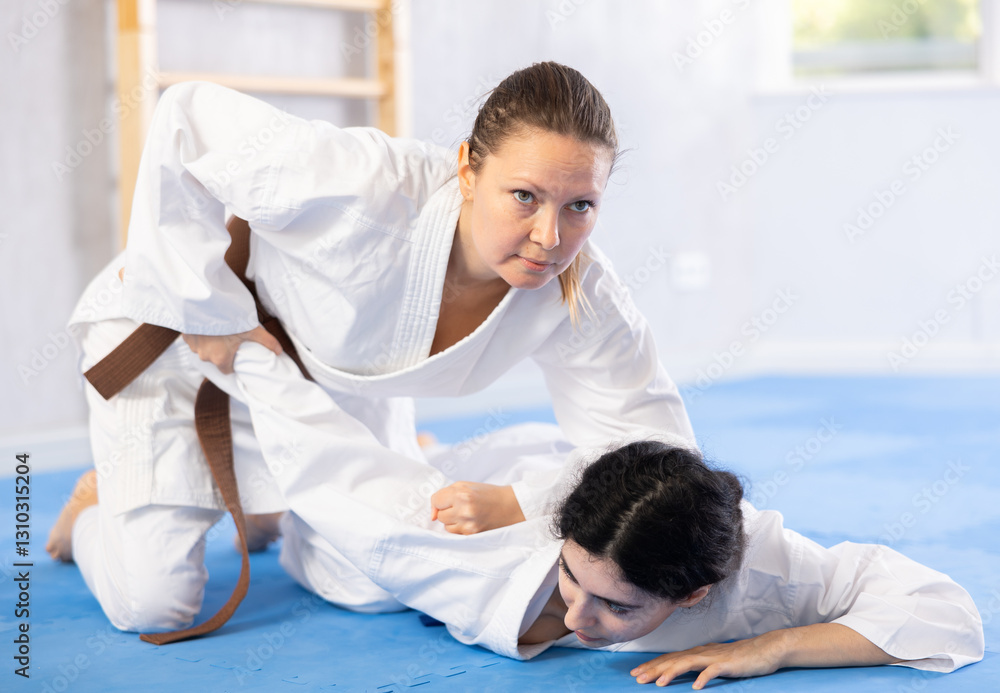 Obraz premium Young woman and adult woman practicing judo technique in gym