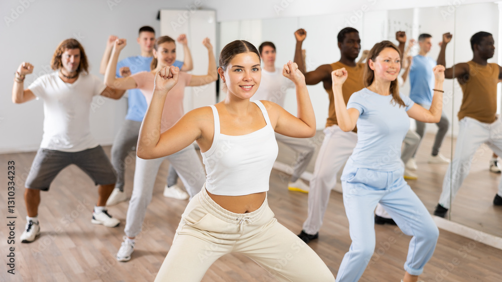 Fototapeta premium Cheerful energetic multiracial dancers of different ages dancing aerobics at lesson in modern class of gym
