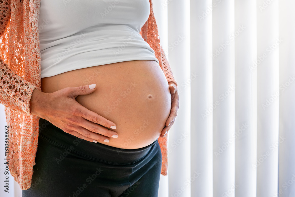 Close-up view of a pregnant woman holding her belly as a concept for maternity