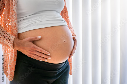 Obraz na płótnie Close-up view of a pregnant woman holding her belly as a concept for maternity w salonie
