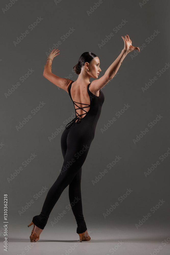 Female dancer in black bodysuit performing contemporary Latin dance pose on gray studio Female dancer in black bodysuit performing contemporary Latin dance pose on gray studio