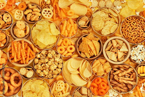 Colorful mix of salty snacks for beer varieties: chips and pretzels, onion rings and crackers. Non-healthy junk food background