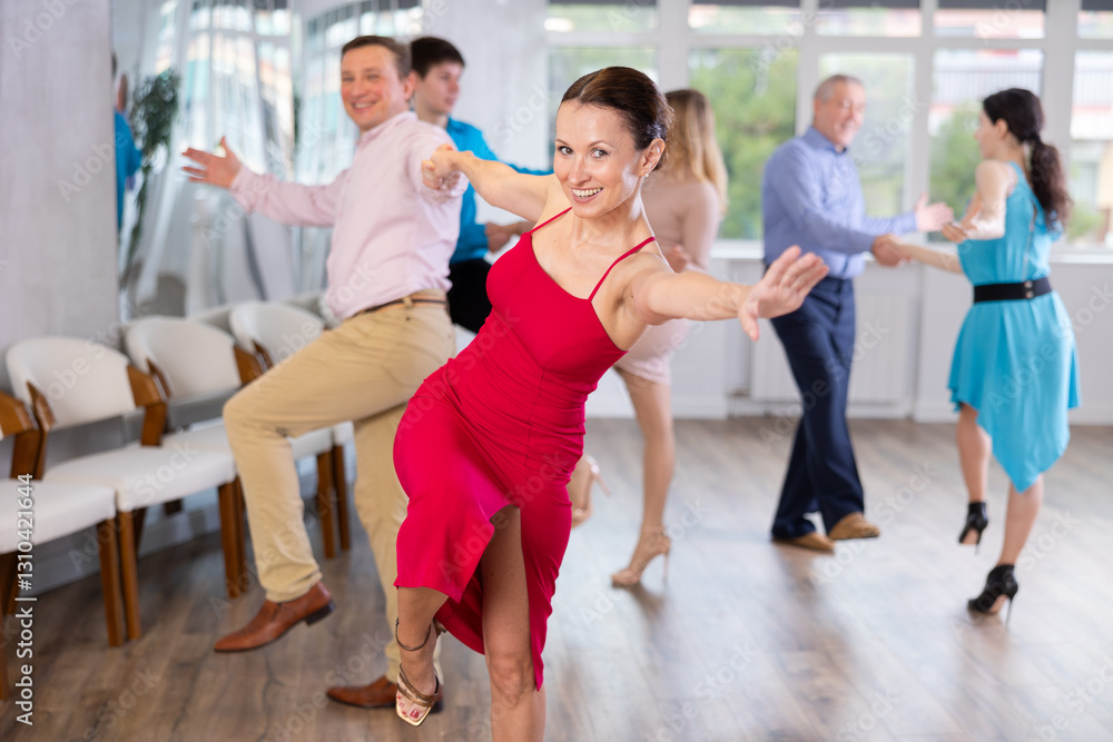 Naklejka premium Enthusiastic woman attending group choreography class, learning modern dynamic dances with male partner. Adult hobbies concept..