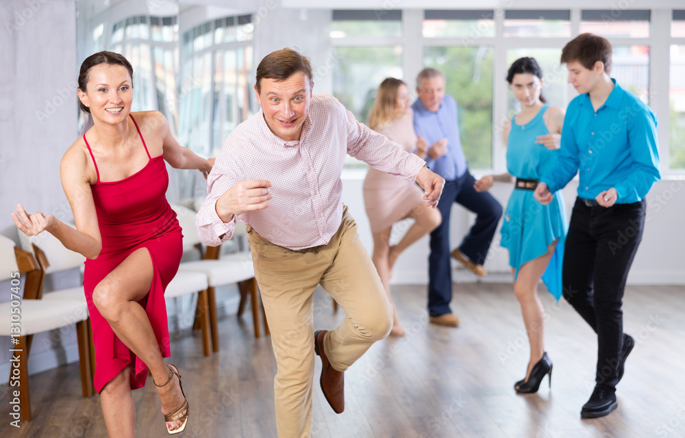 Fototapeta premium Group is of different ages active people engaged in Latin dance studio and learns movements of cha-cha-cha dance
