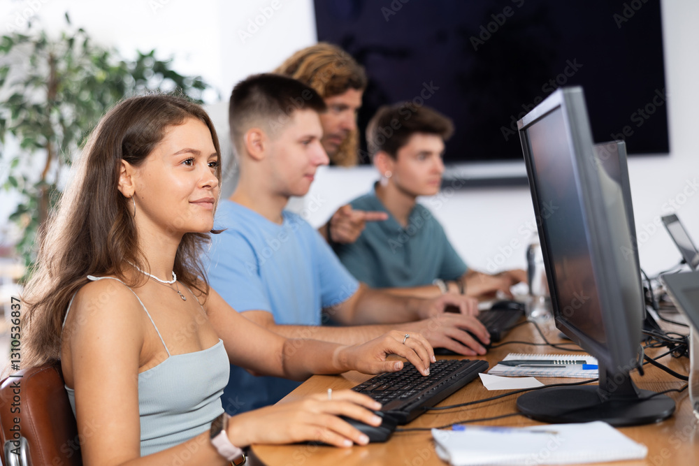 Female student of computer courses attentively looks at monitor screen, types on keyboard and completes work Female student of computer courses attentively looks at monitor screen, types on keyboard and completes work