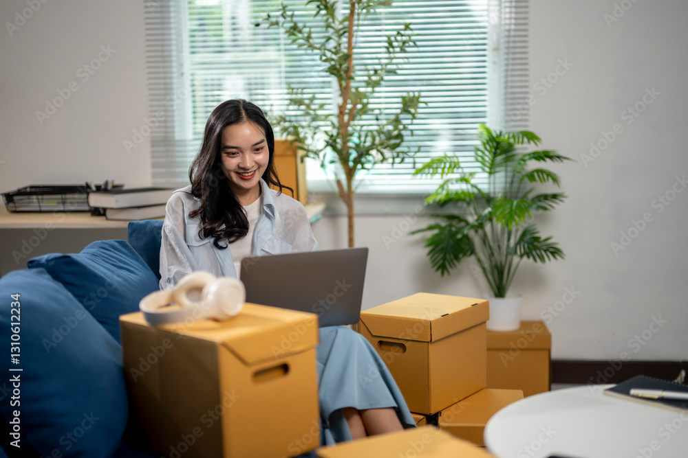 A woman is sitting on a couch in a room with boxes around her A woman is sitting on a couch in a room with boxes around her