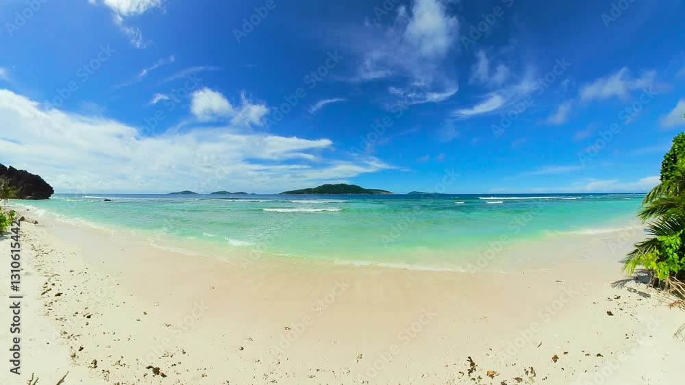 Soft sandy beach with turquoise waves and green palm trees under a clear sky. Seychelles, La Digue. Soft sandy beach with turquoise waves and green palm trees under a clear sky. Seychelles, La Digue.