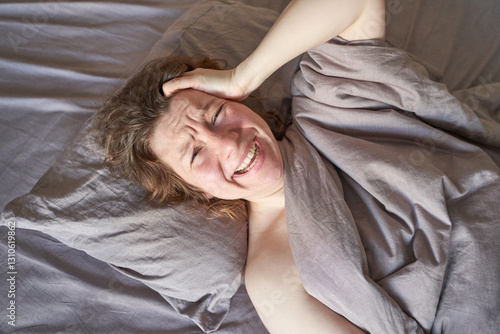 Photos Caucasian mature female lying in bed expressing discomfort and holding head with hand