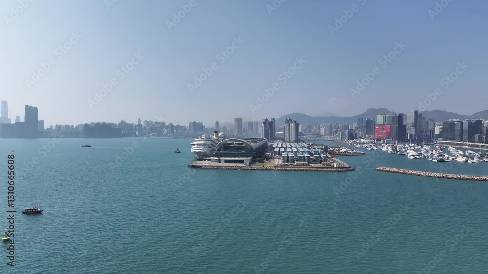 Drone aerial skyview of a mega luxury cruise ship sailing at the Kai Tak cruise terminal, showcasing the vibrant Victoria Harbour and the iconic city skyline of Kwun Tong Kowloon Hong Kong Drone aerial skyview of a mega luxury cruise ship sailing at the Kai Tak cruise terminal, showcasing the vibrant Victoria Harbour and the iconic city skyline of Kwun Tong Kowloon Hong Kong