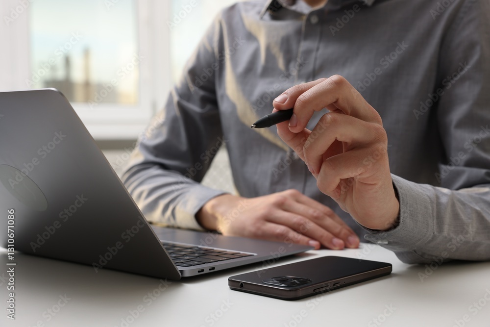 Electronic signature. Man with stylus, laptop and smartphone at white table indoors, closeup Electronic signature. Man with stylus, laptop and smartphone at white table indoors, closeup