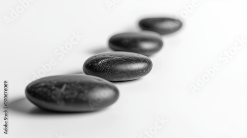 Arranged black river stones on pure white surface create calming and meditative atmosphere, perfect for wellness concepts
