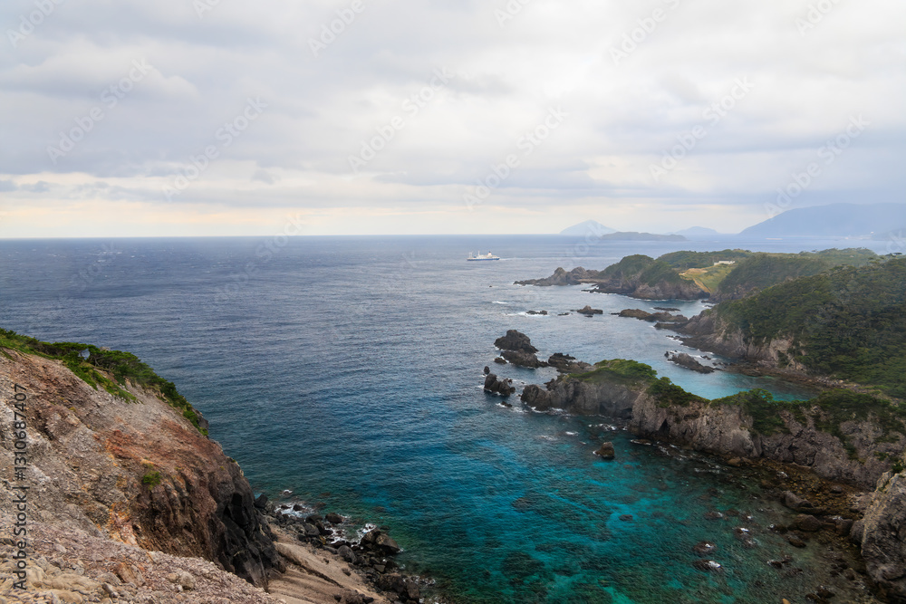 Fototapeta premium 青い海と緑の森が美しい神引展望台から見る、沖を航行する大型客船（さるびあ丸）と式根島と新島の海。東京都伊豆諸島式根島 -2024 