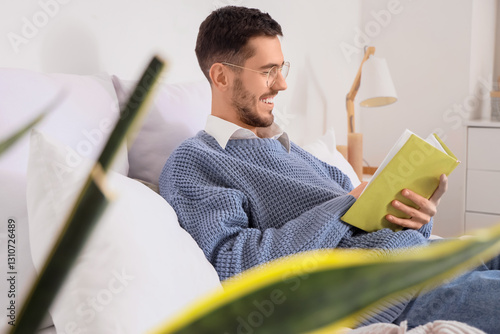 Young man reading book in b...