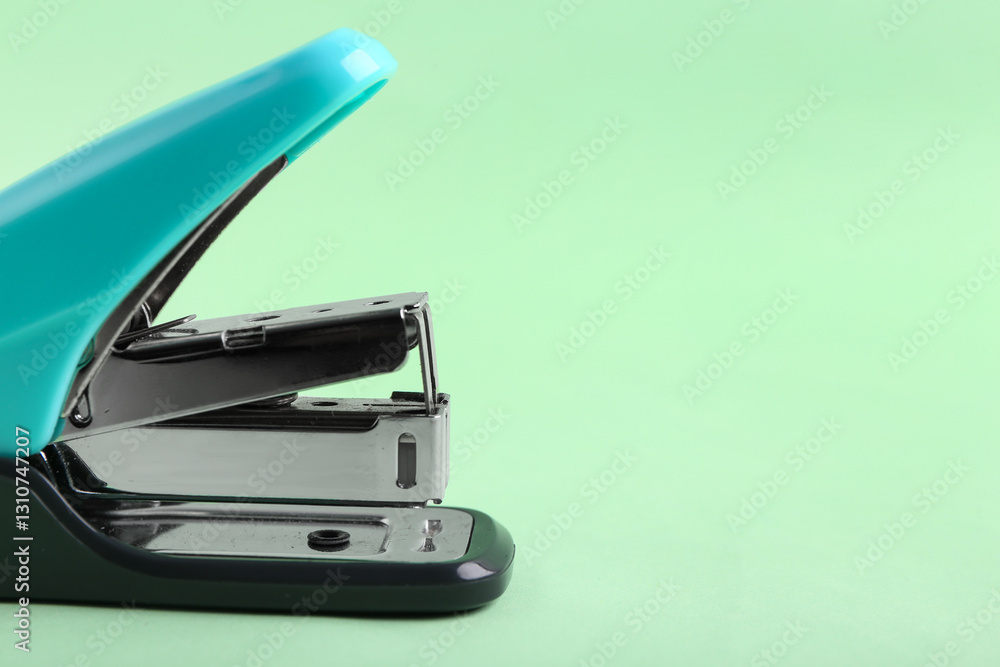 Blue stapler on green background, closeup Blue stapler on green background, closeup